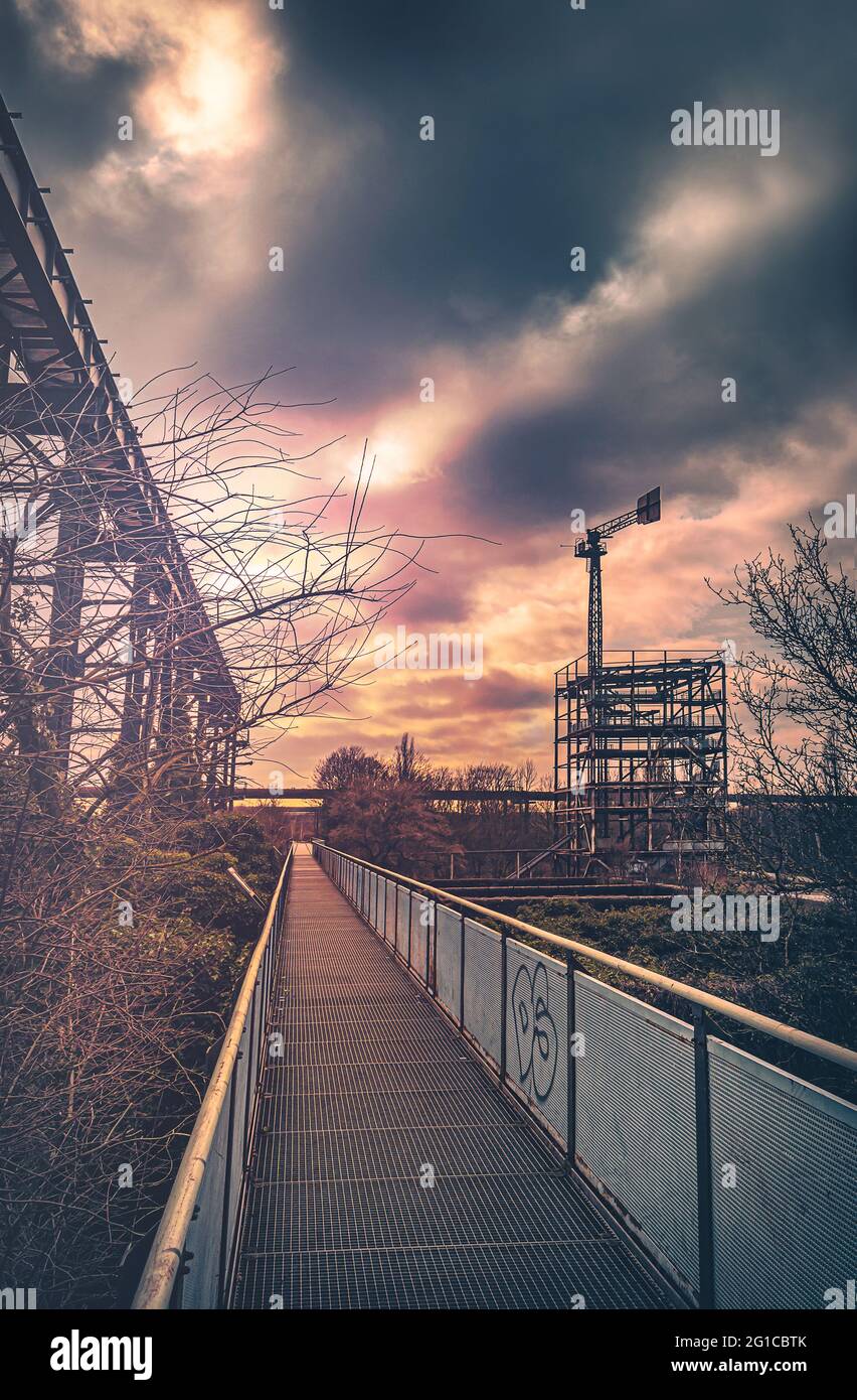 Metal and steel promenade on the Emscher in central perspective. Duisburg Landscape Park. Industrial machines and rusted components in the Ruhr area. Stock Photo