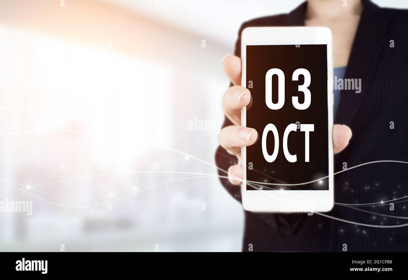 October 3rd. Day 3 of month, Calendar date. White smartphone with Calendar date in businesswoman hand on blurred background. Autumn month, day of the Stock Photo