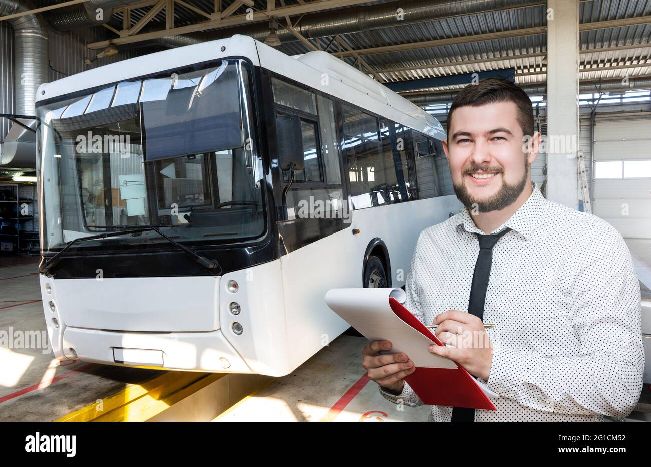 Serviceman with notepad on the background of the bus in the garage Stock Photo