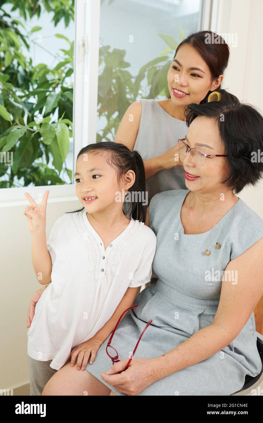 Happy smiling young senior woman, her daughter and little granddaughter posing for photo Stock Photo