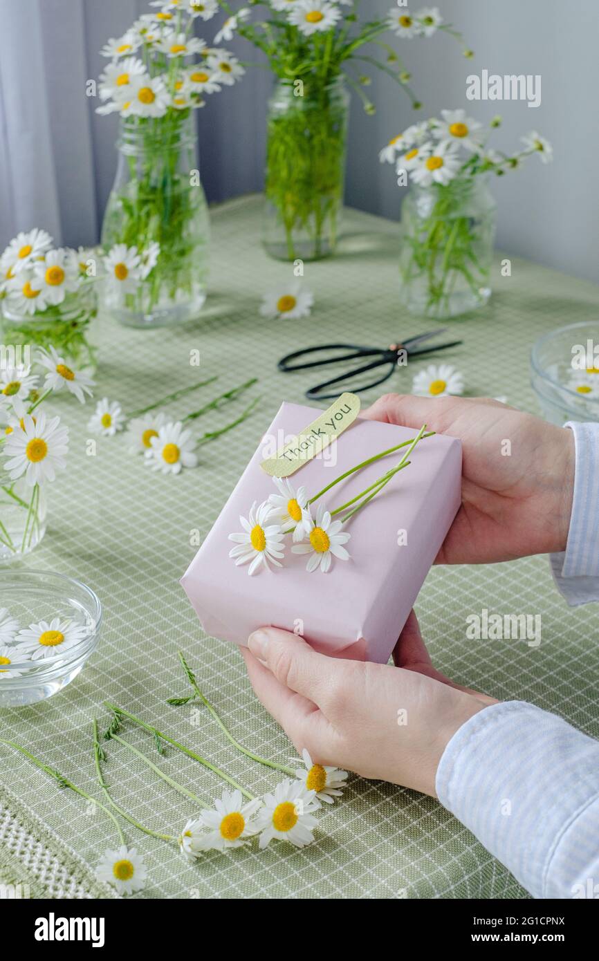 Female hands holding a gift decorated with chamomile flowers with words of gratitude. High quality photo Stock Photo