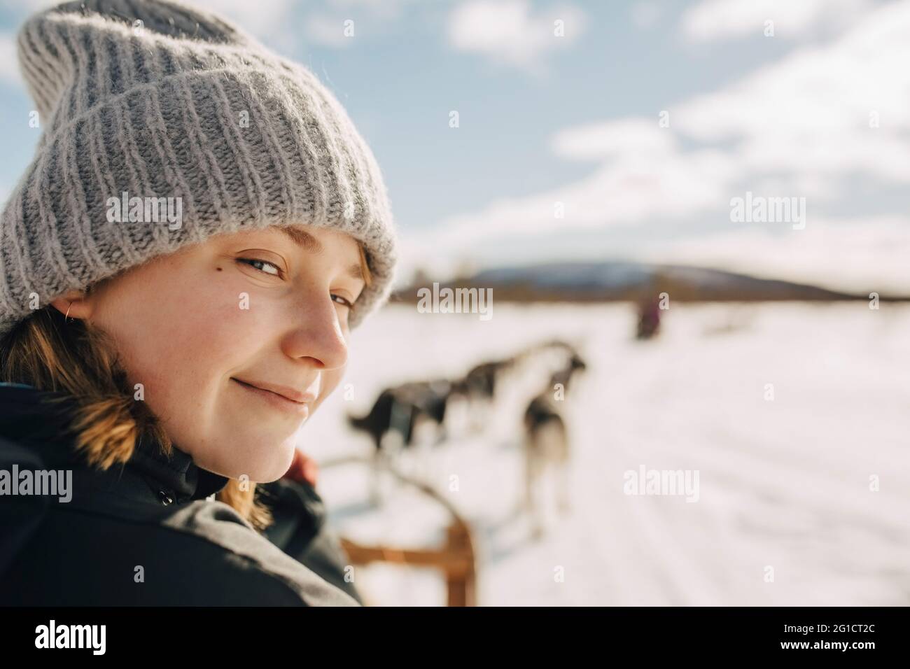 Portrait of teenage girl wearing knit hat doing dogsledding during winter Stock Photo