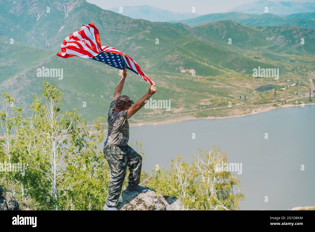 Man in military uniform holding an American flag above his head Stock Photo