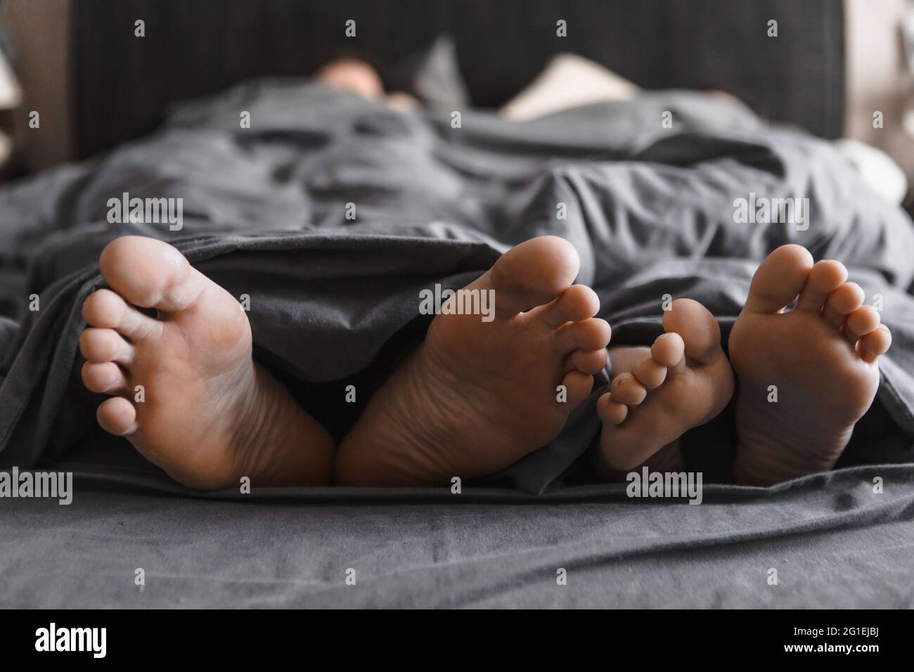 couple feet under the blanket in bed with grey sheets close up copy space Stock Photo Alamy
