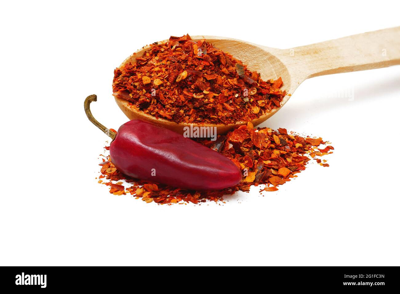 ground dried chili pepper flakes in wooden spoon and pod isolated on