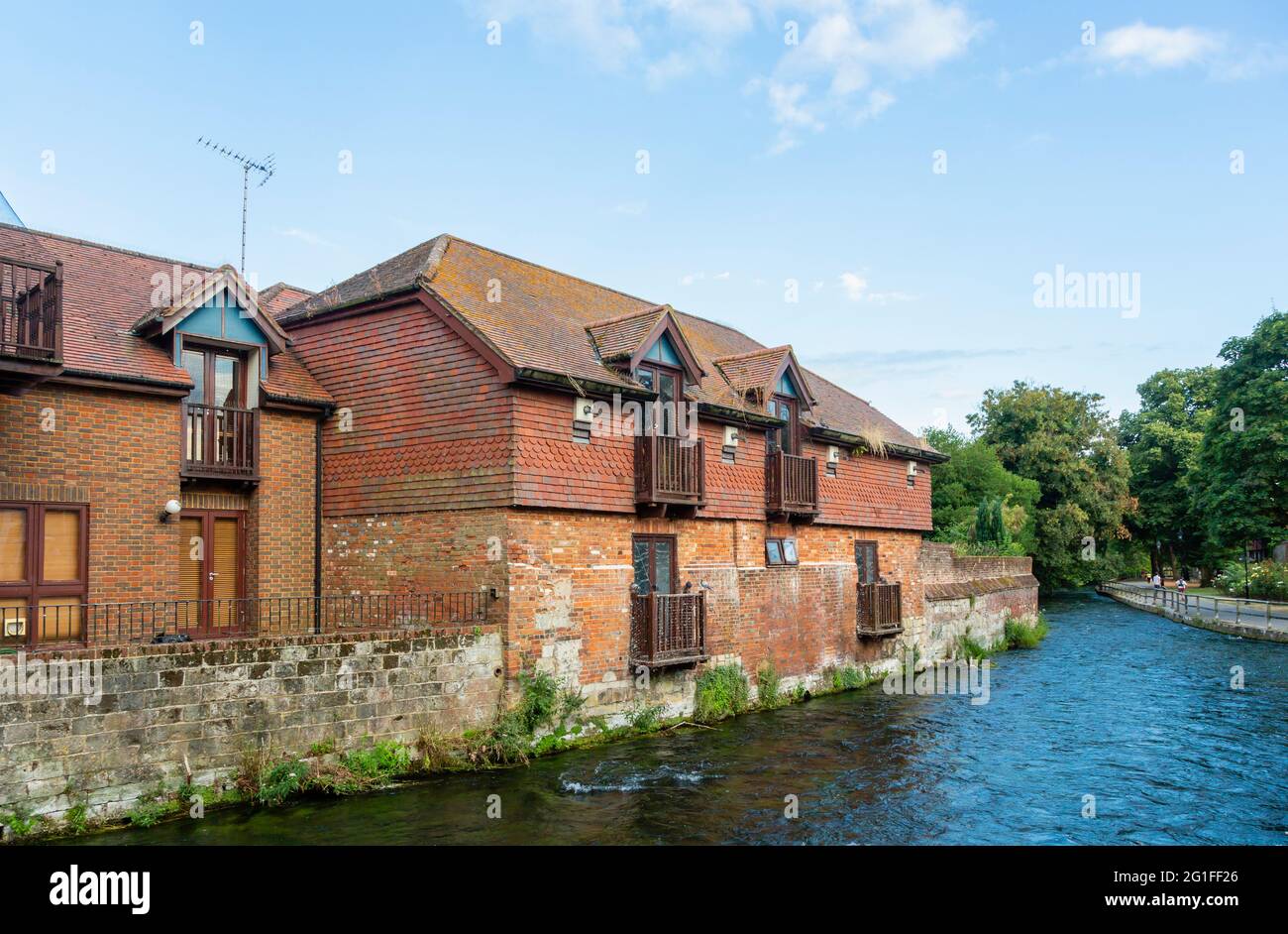 The River Itchen flowing past historic riverside buildings converted for residential housing use at The Weirs in Winchester, Hampshire, south England Stock Photo