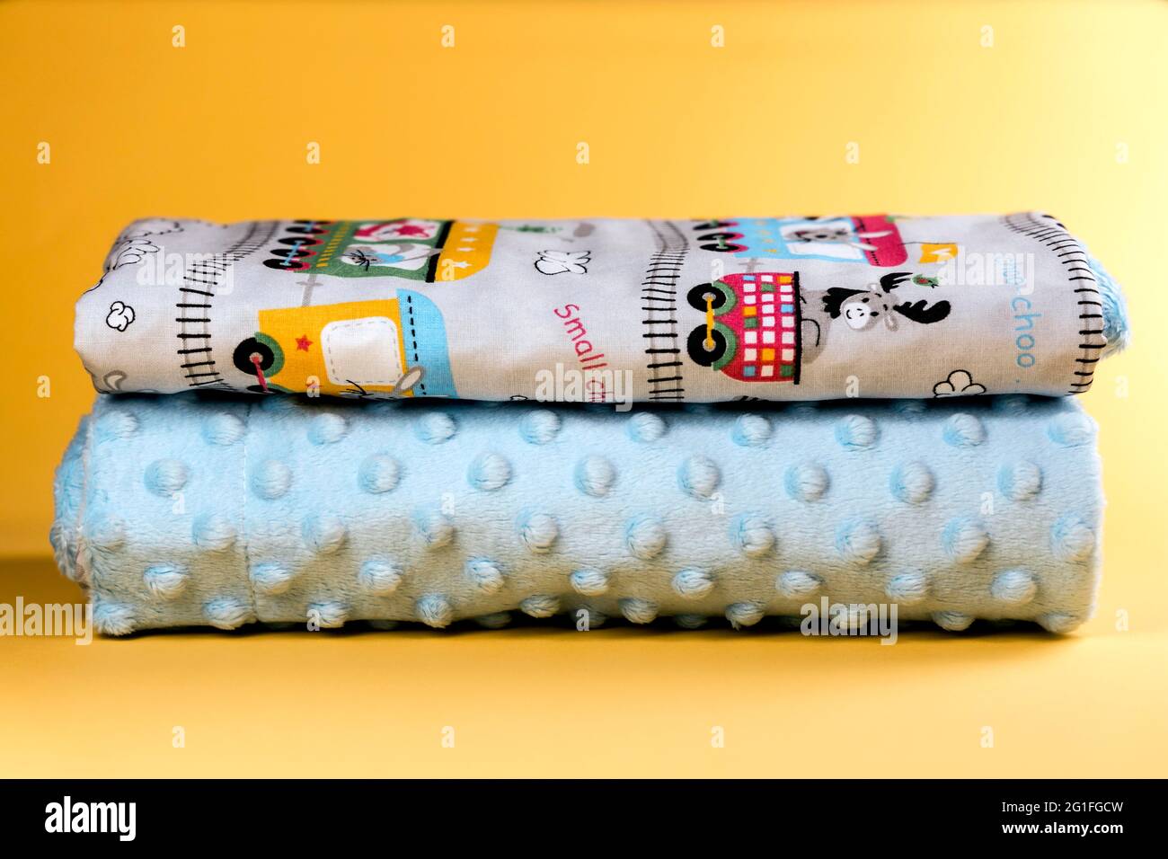 Sweet and cozy baby blanket with train pattern isolated on yellow background Stock Photo