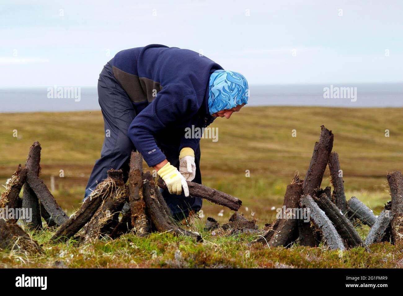 Peat digger, old woman, headscarf, peat cutting, peat bog, manual peat cutting, peat sod drying, peat pile, Tabost, Isle of Lewis, Outer Hebrides Stock Photo