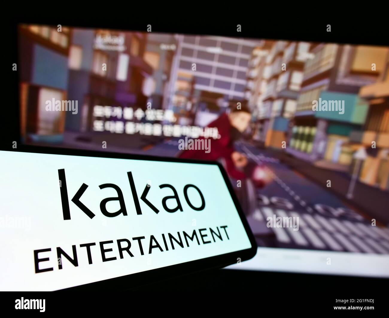 Cellphone with logo of South Korean company Kakao Entertainment Corp. on screen in front of business webpage. Focus on center-left of phone display. Stock Photo