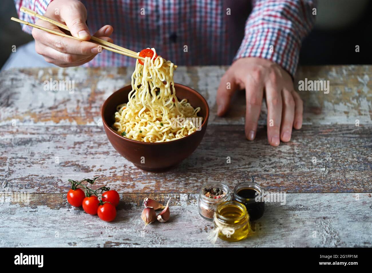 Male hands are eating Chinese noodles with chopsticks. Chinesestyle