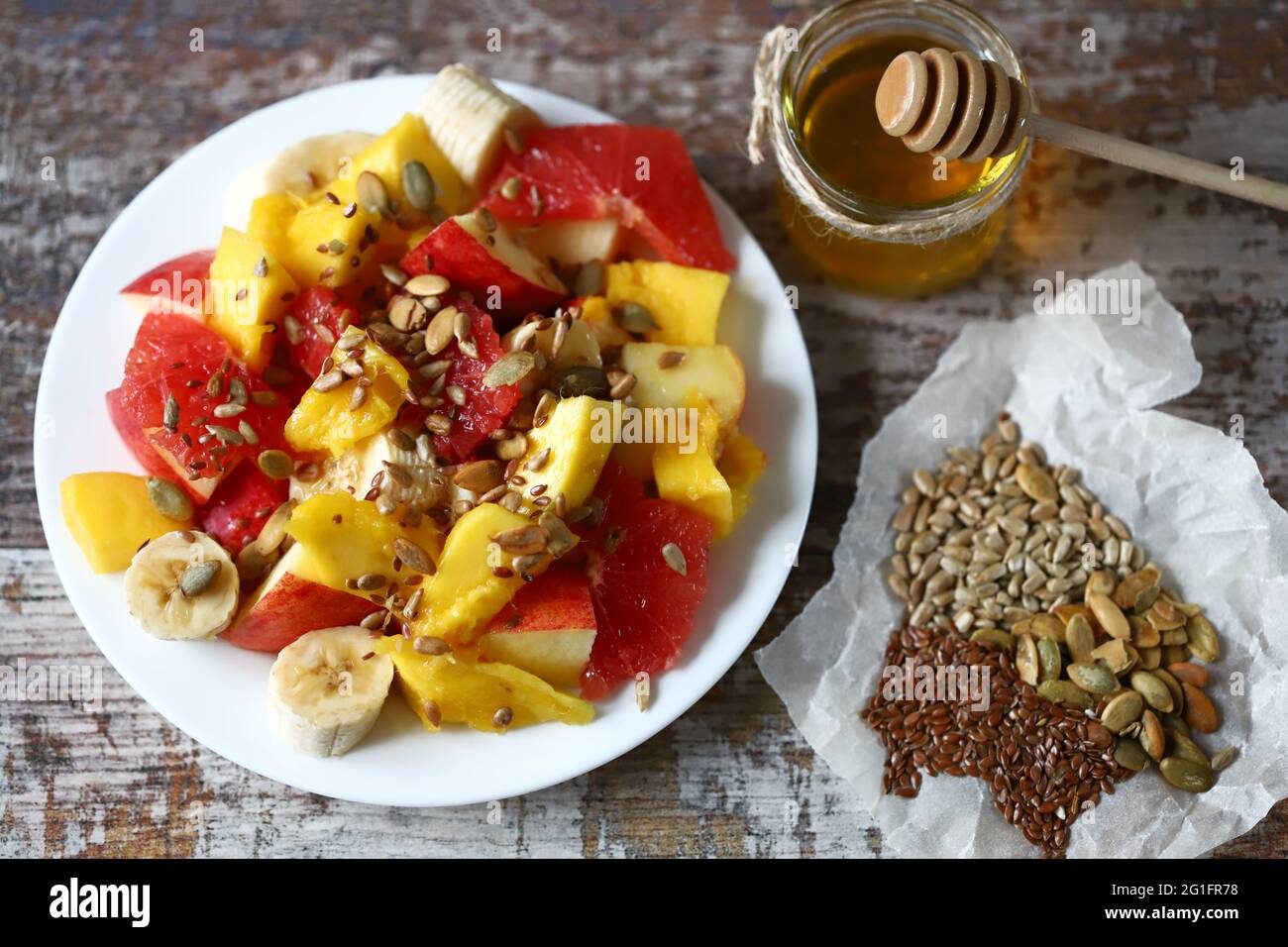 Fresh juicy fruit salad on a plate with mango, grapefruit and seeds