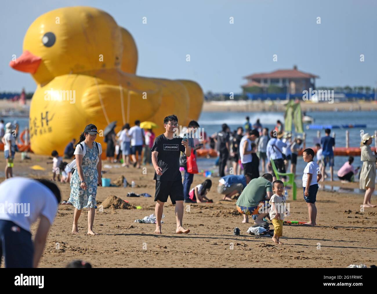 (210607) -- TIANJIN, June 7, 2021 (Xinhua) -- Tourists have fun at an artificial beach resort at Dongjiang Port in the Binhai New Area of north China's Tianjin, June 5, 2021. Tianjin in north China boasts rich biodiversity along a 153-km coastline made up of muddy tidal flats. Over the years, the city has worked on pollution control and shoreline management of the Bohai Sea to restore its coastal wetlands, while stricter measures on land reclamation have been implemented. In 2020, 70.4 percent of Tianjin's offshore waters achieved sound quality under a three-year action plan to battle wat Stock Photo
