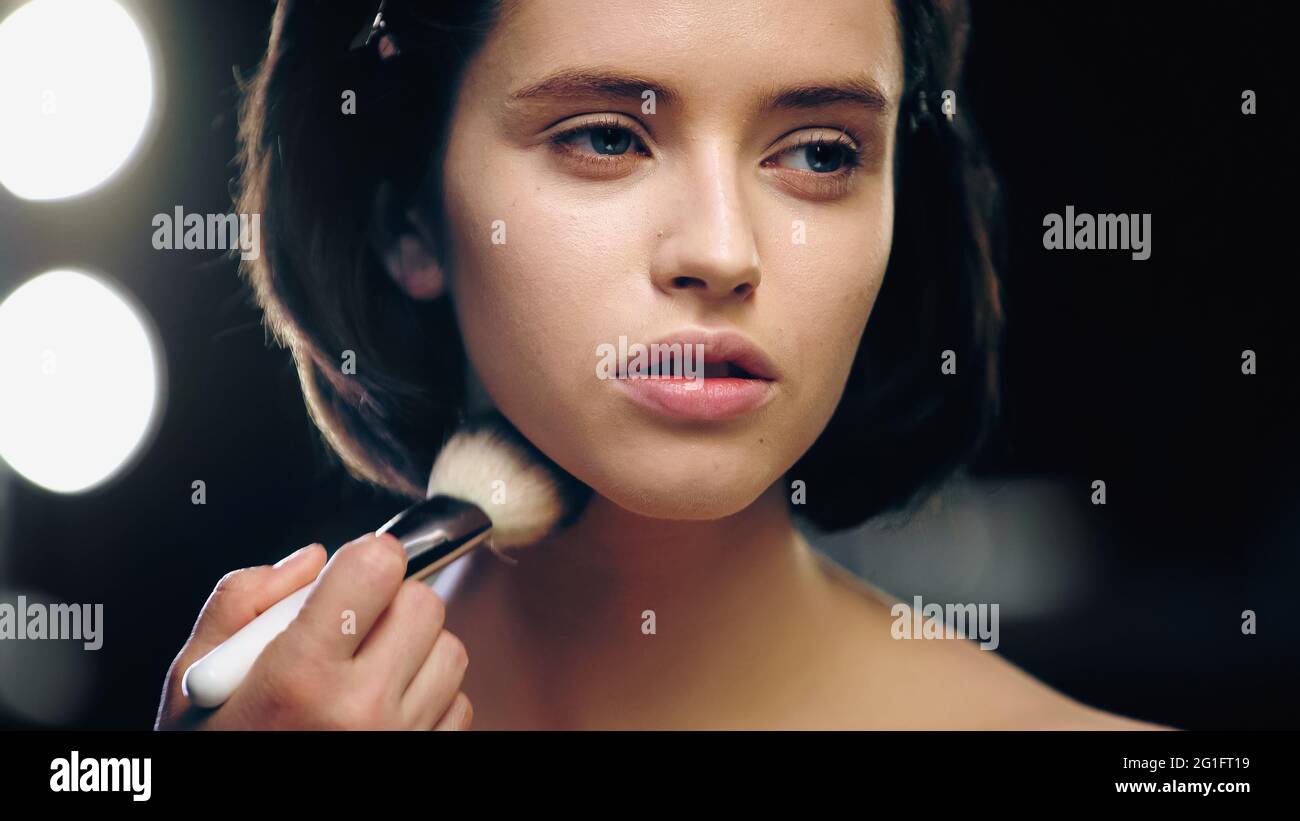 makeup artist applying powder on face of pretty model Stock Photo