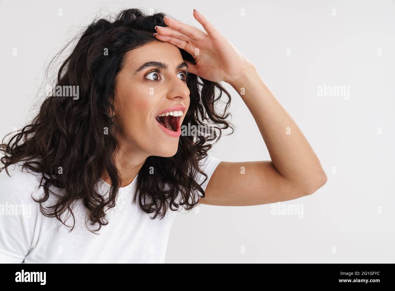 Excited brunette girl expressing surprise and looking aside isolated ...