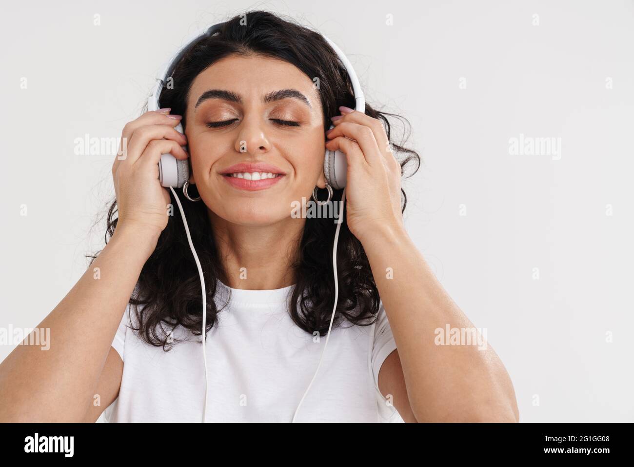 Happy brunette girl smiling while listening music with headphones ...