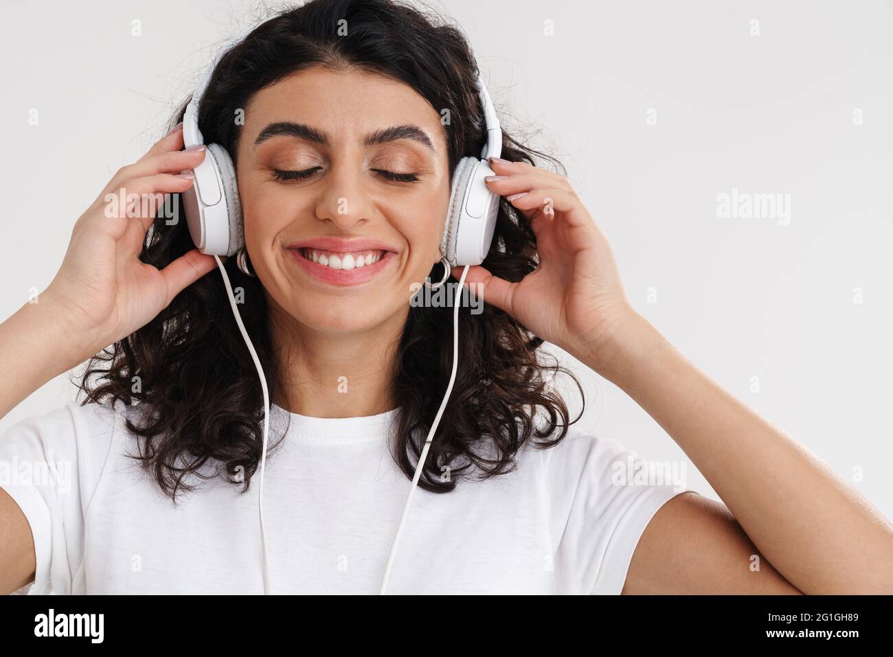 Happy brunette girl smiling while listening music with headphones ...