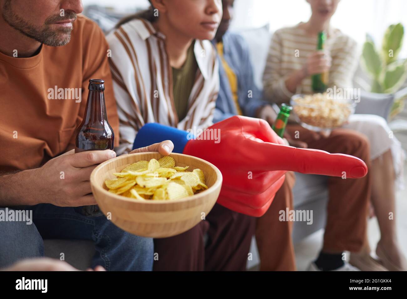 Close up of group of people holding snacks and fan gear while watching sports match together, copy space Stock Photo