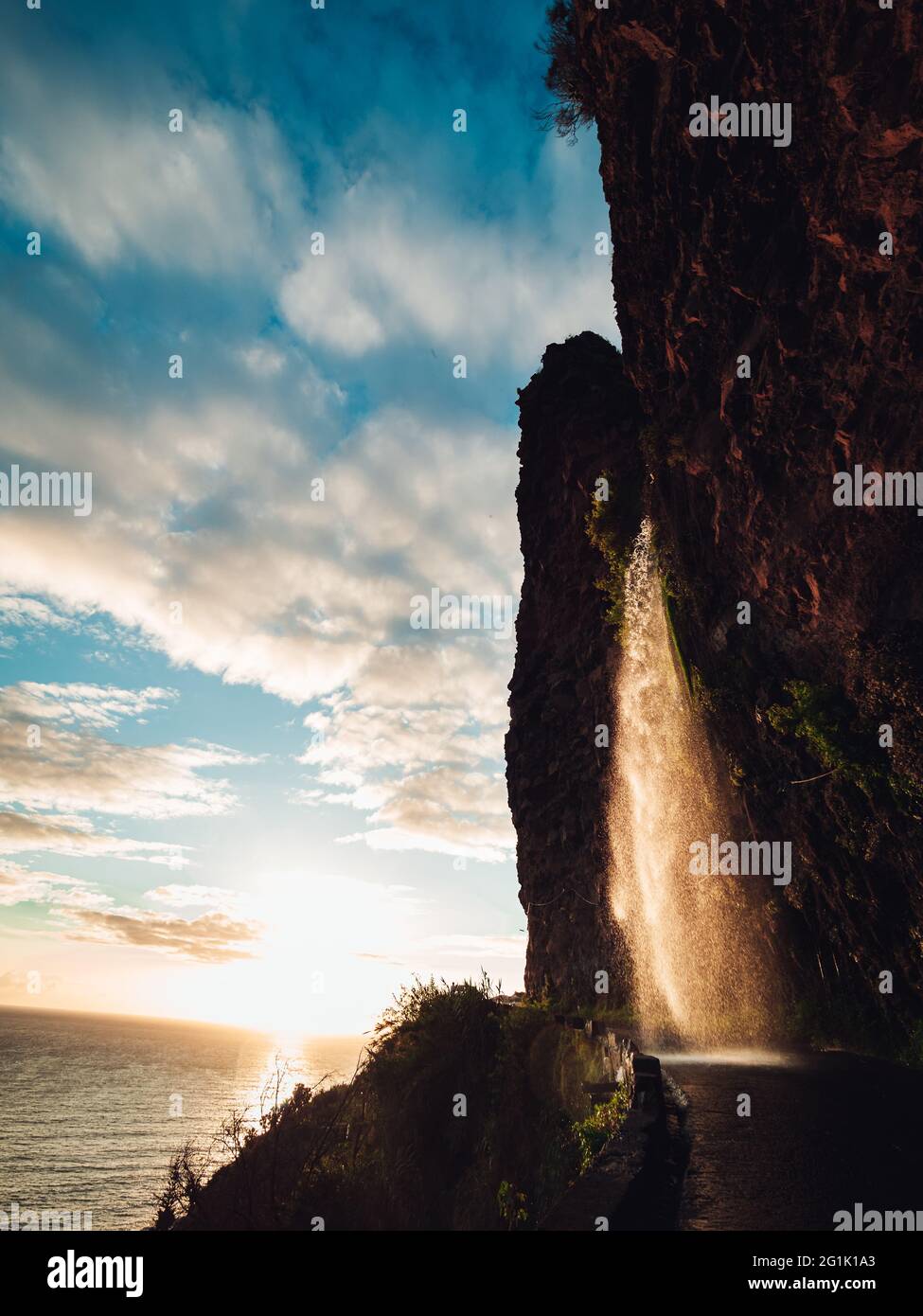 Vertical side view of a foamy waterfall over rocks shining under the ...