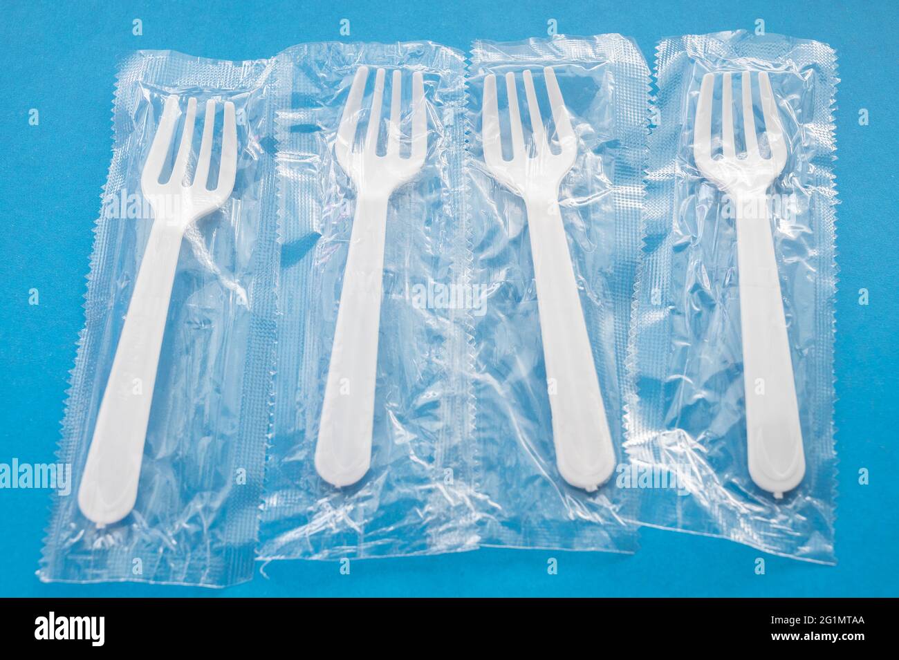 Disposable plastic forks on a blue background Stock Photo Alamy