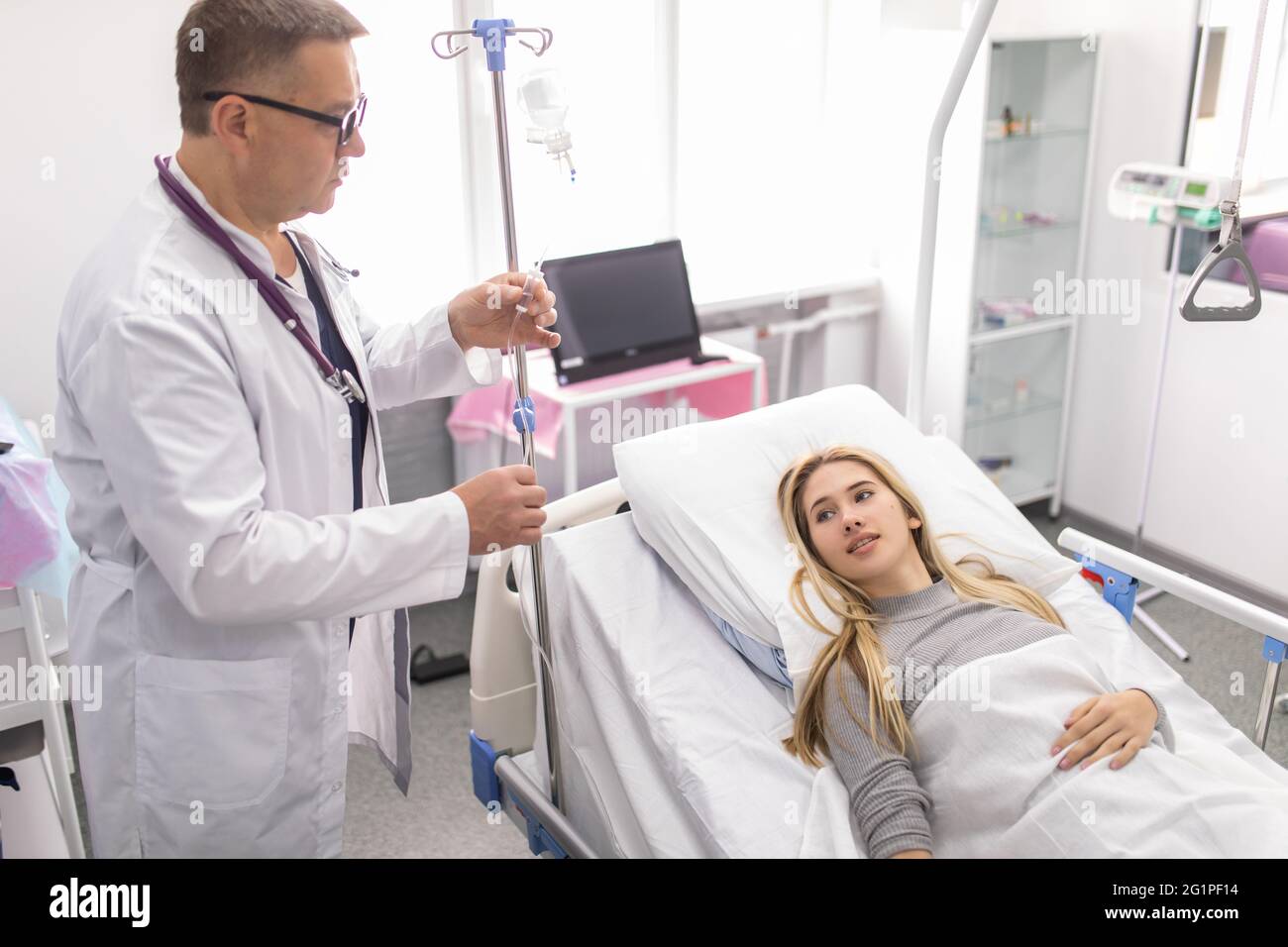 Mature Doctor working, checking Intravenous drip, I.V. tube saline fluid  bag for cure patient in hospital room. Handsome professional doctor care  his Stock Photo - Alamy