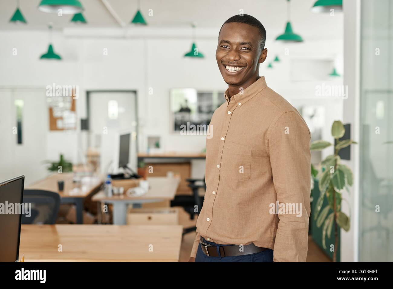 Laughing young African businessman standing alone in an office Stock ...
