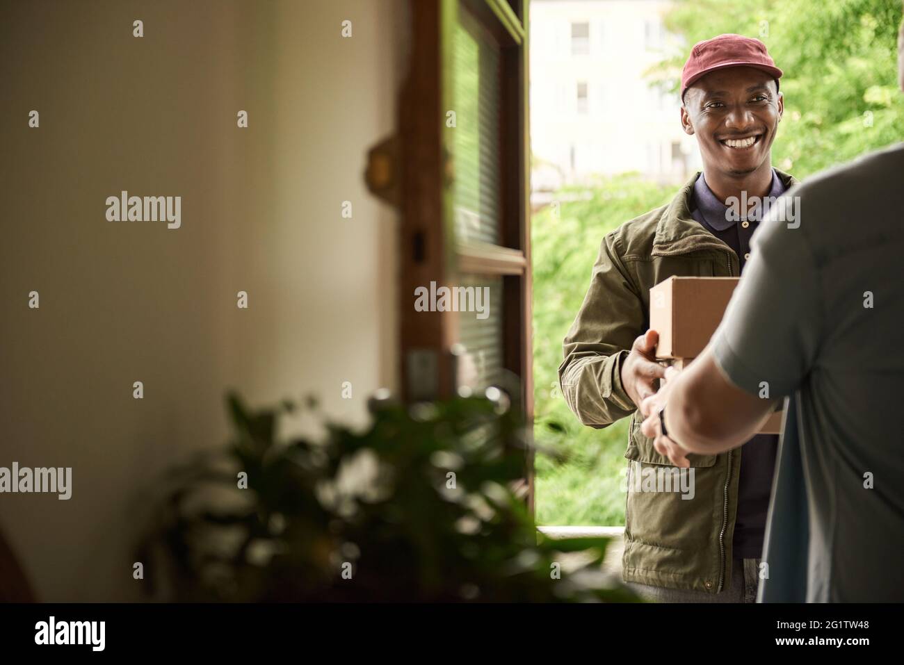 Smiling African courier handing packages to a customer Stock Photo