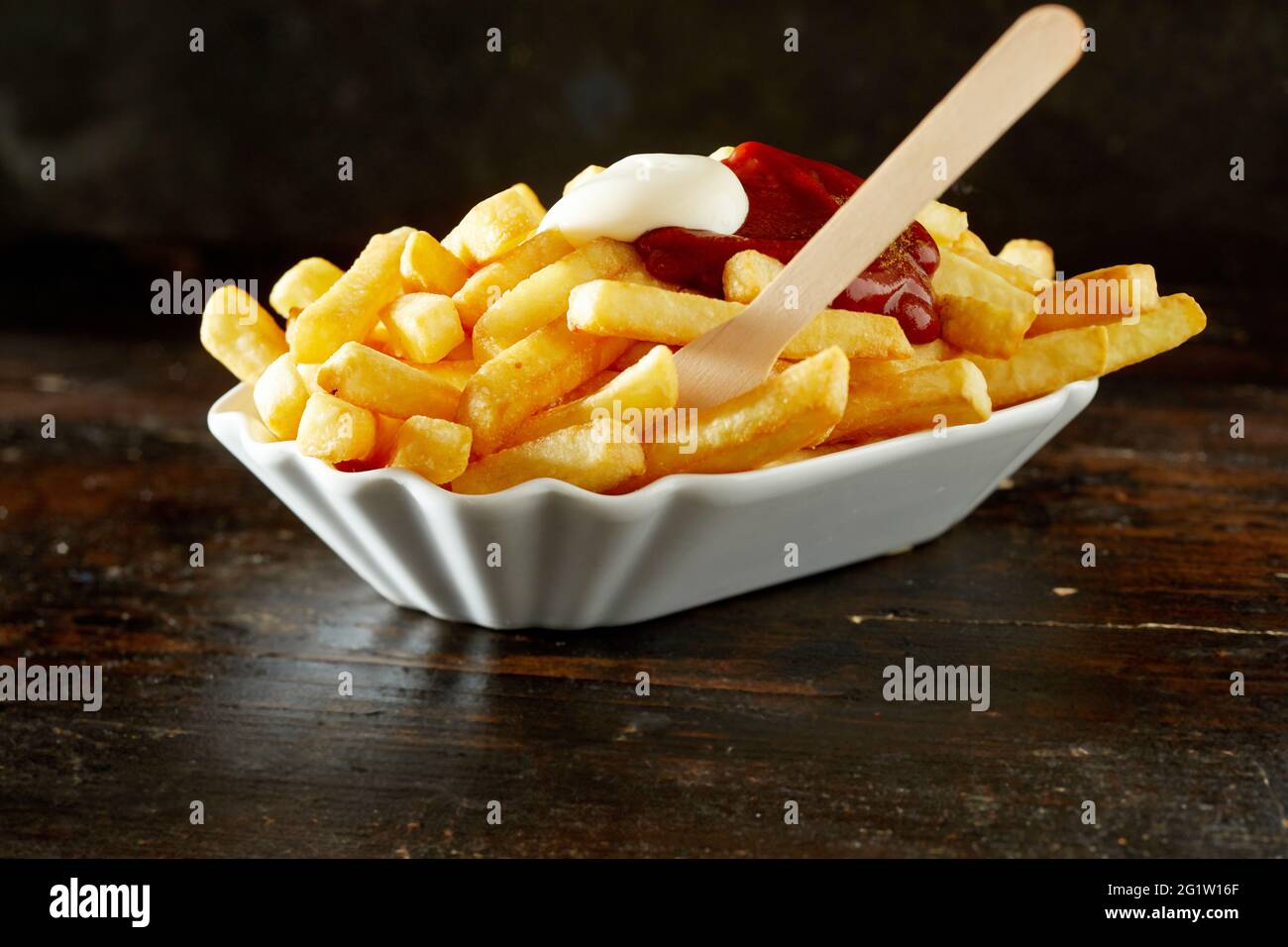 Yummy deep fried potato slices with mayo and ketchup in porcelain bowl
