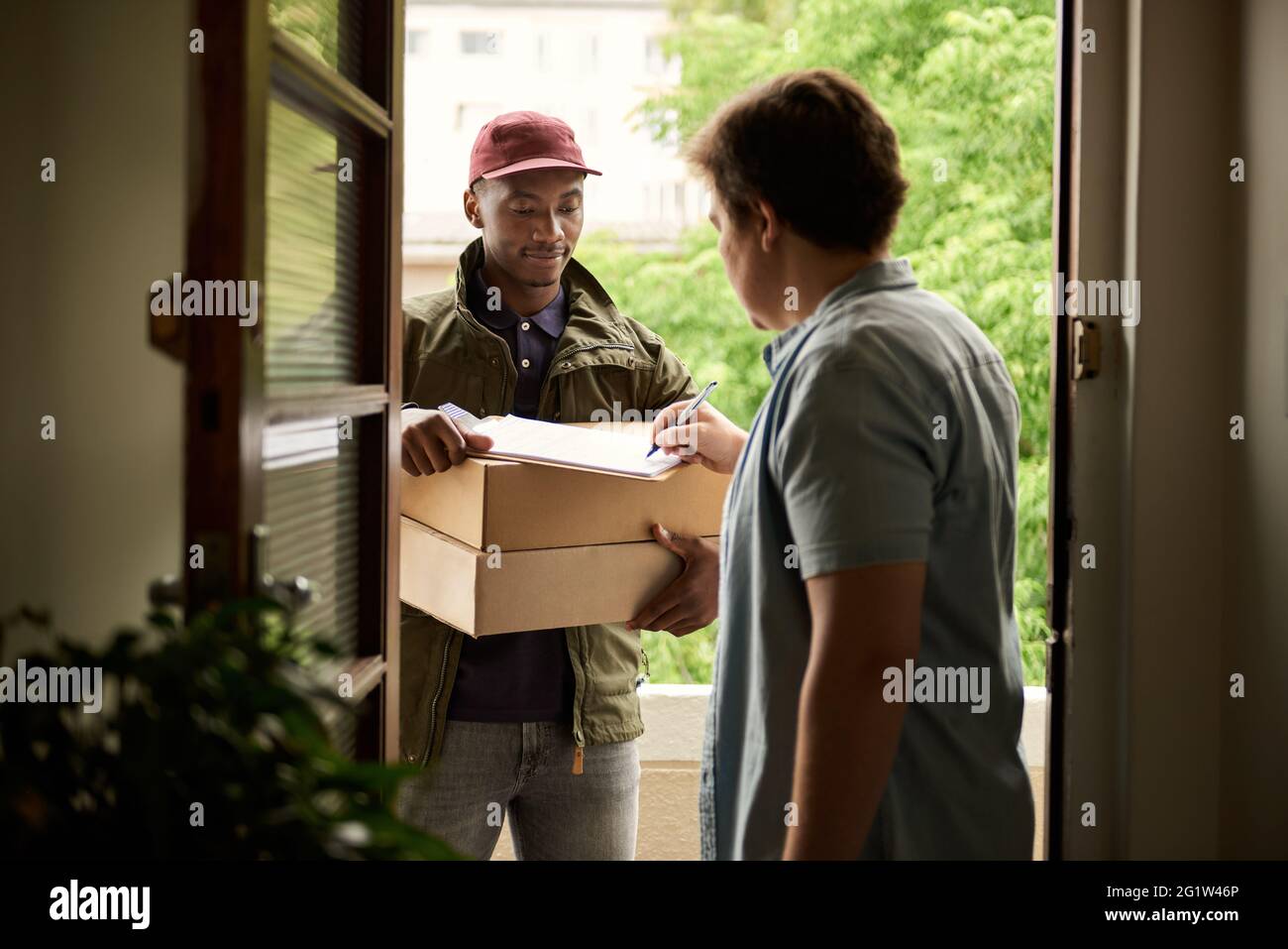 Man signing for a courier package at his front door Stock Photo