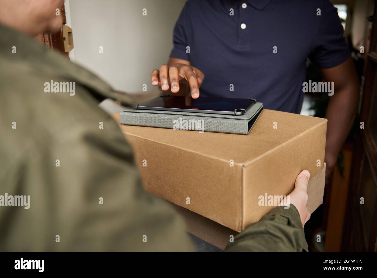 African man signing a courier's tablet to receive a package Stock Photo