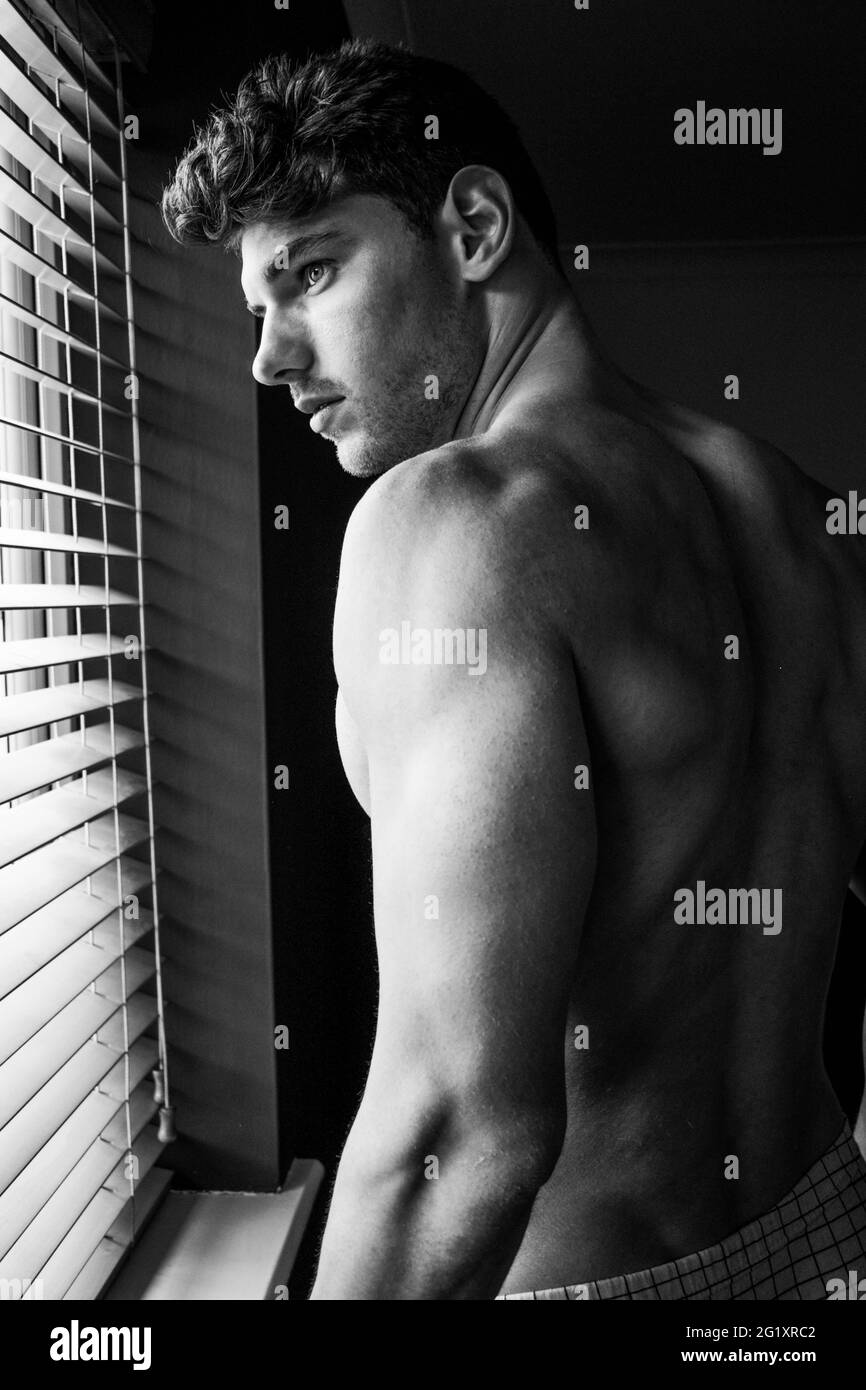 Black and white portrait of attractive shirtless man showing muscular arms, shoulders and back. Stock Photo