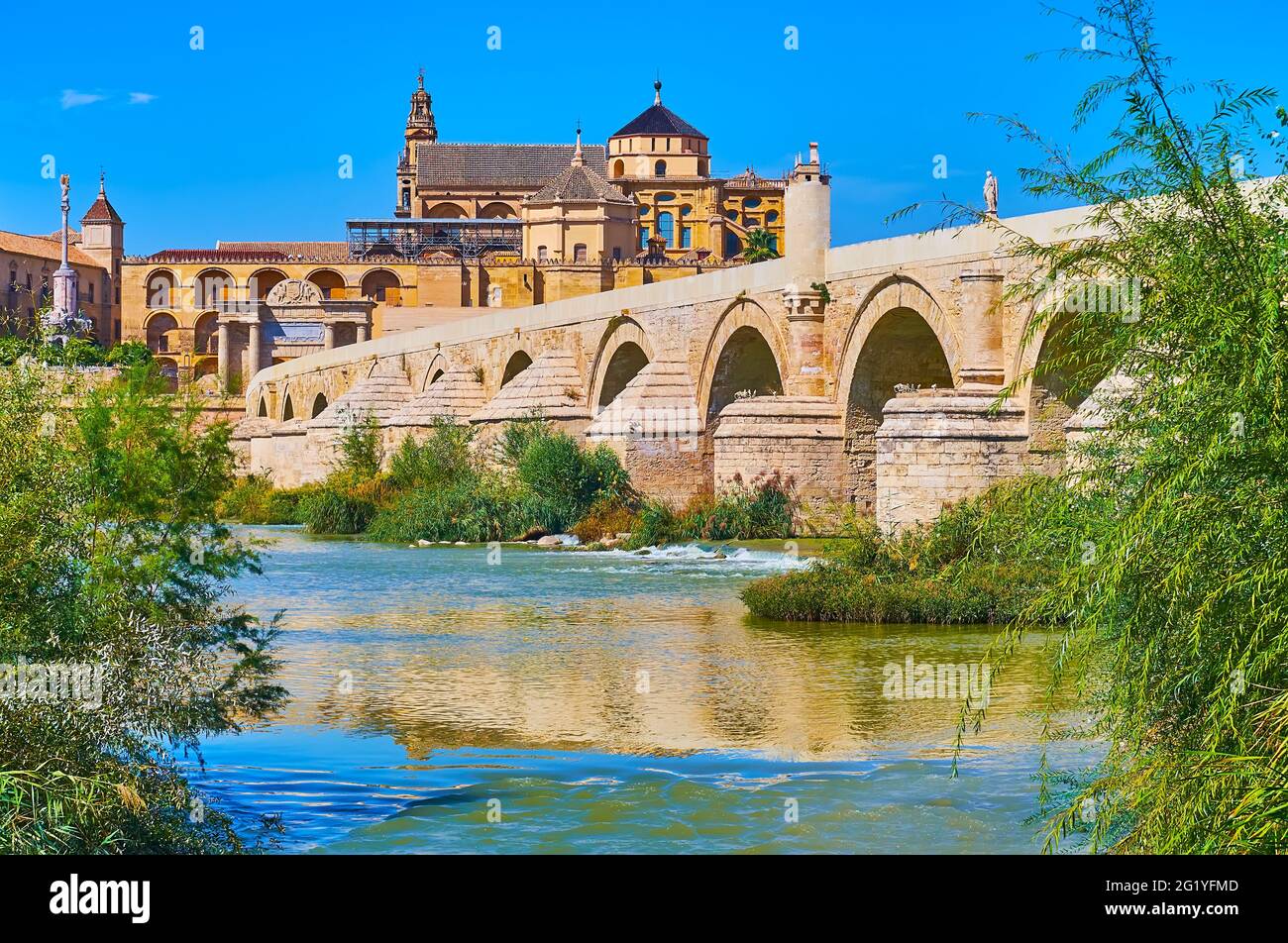 The monumental building of Mezquita-Catedral (Mosque-Cathedral) is seen behind the Guadalquivir River and the Roman Bridge, Cordoba, Spain Stock Photo
