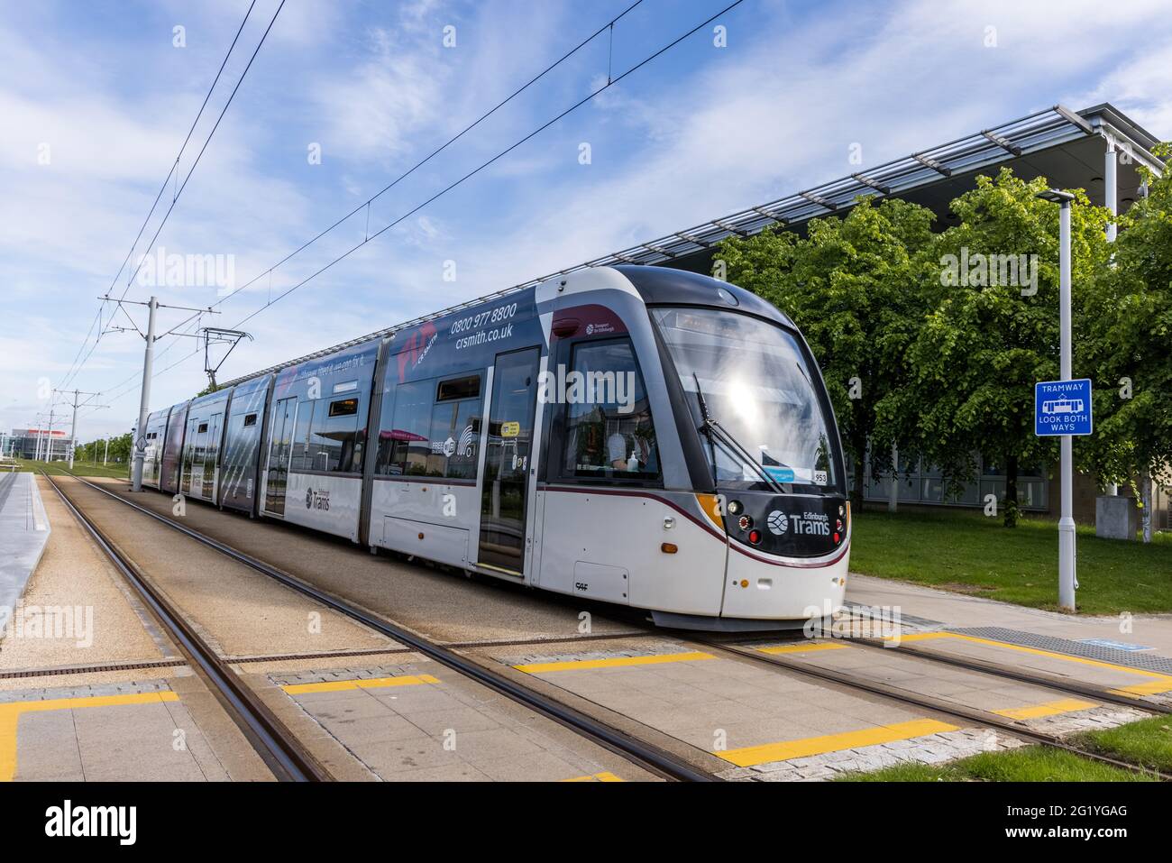 An Edinburgh tram branded with CR Smith advertising at a tram stop in Edinburgh Park on a sunny day Stock Photo