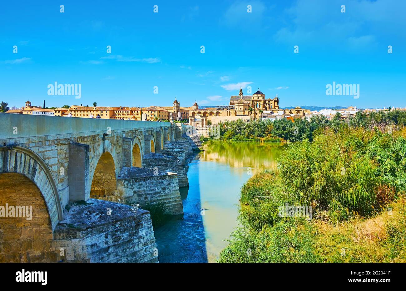 The pleasant walk along the bank of Guadalquivir River with a view of the most significant landmarks of Cordoba - the ancient Roman Bridge and Mezquit Stock Photo