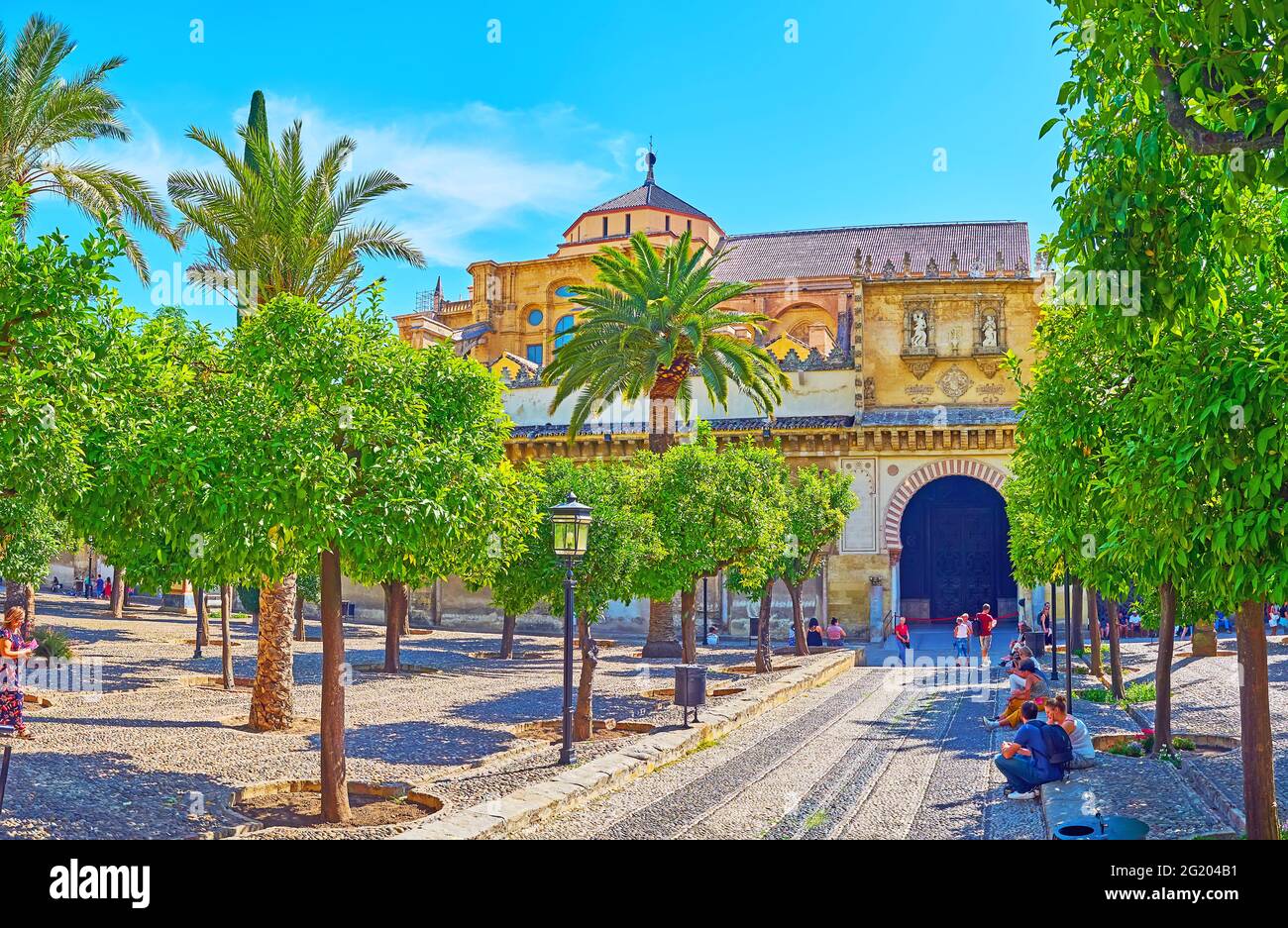 CORDOBA, SPAIN - SEP 30, 2019: The lush garden of Courtyard of the Oranges and the scenic medieval Puerta de las Palmas gate of Mezquita, on Sep 30 in Stock Photo
