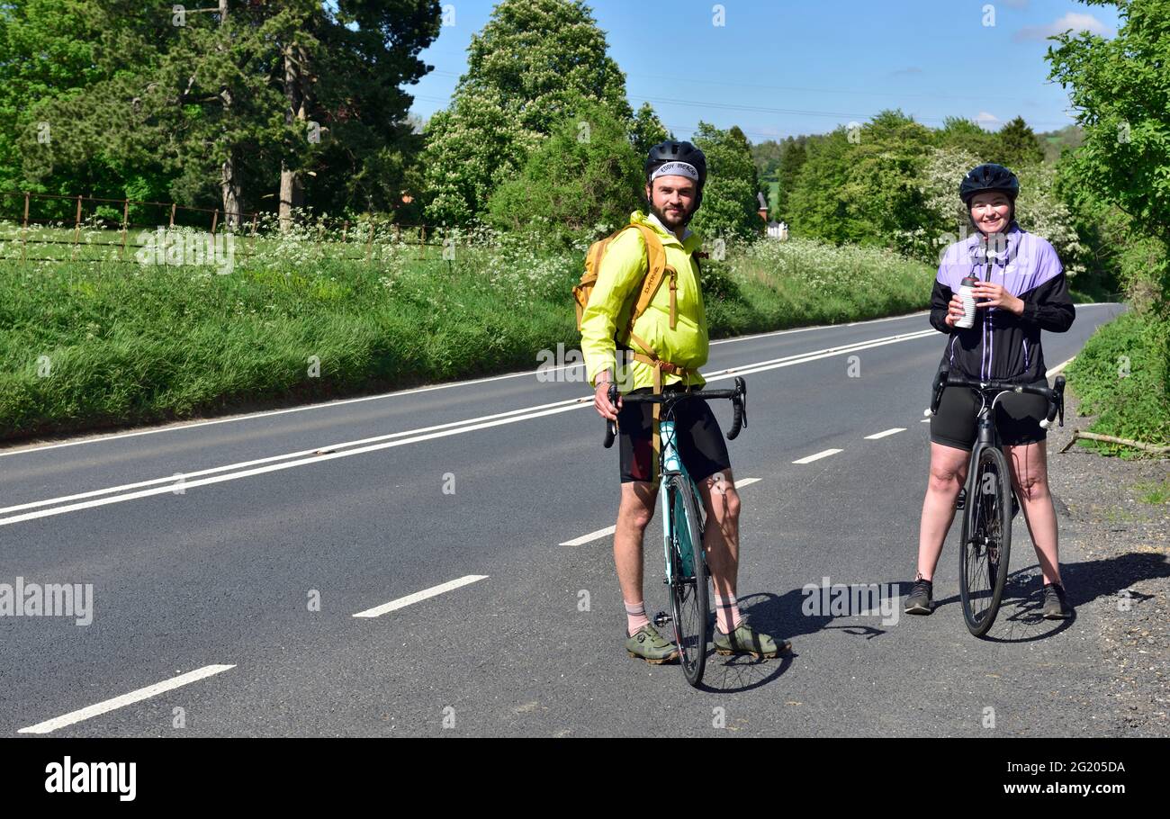 Two cyclists touring the British countryside stopping for rest on Cotswold Way, Gloucestershire Stock Photo