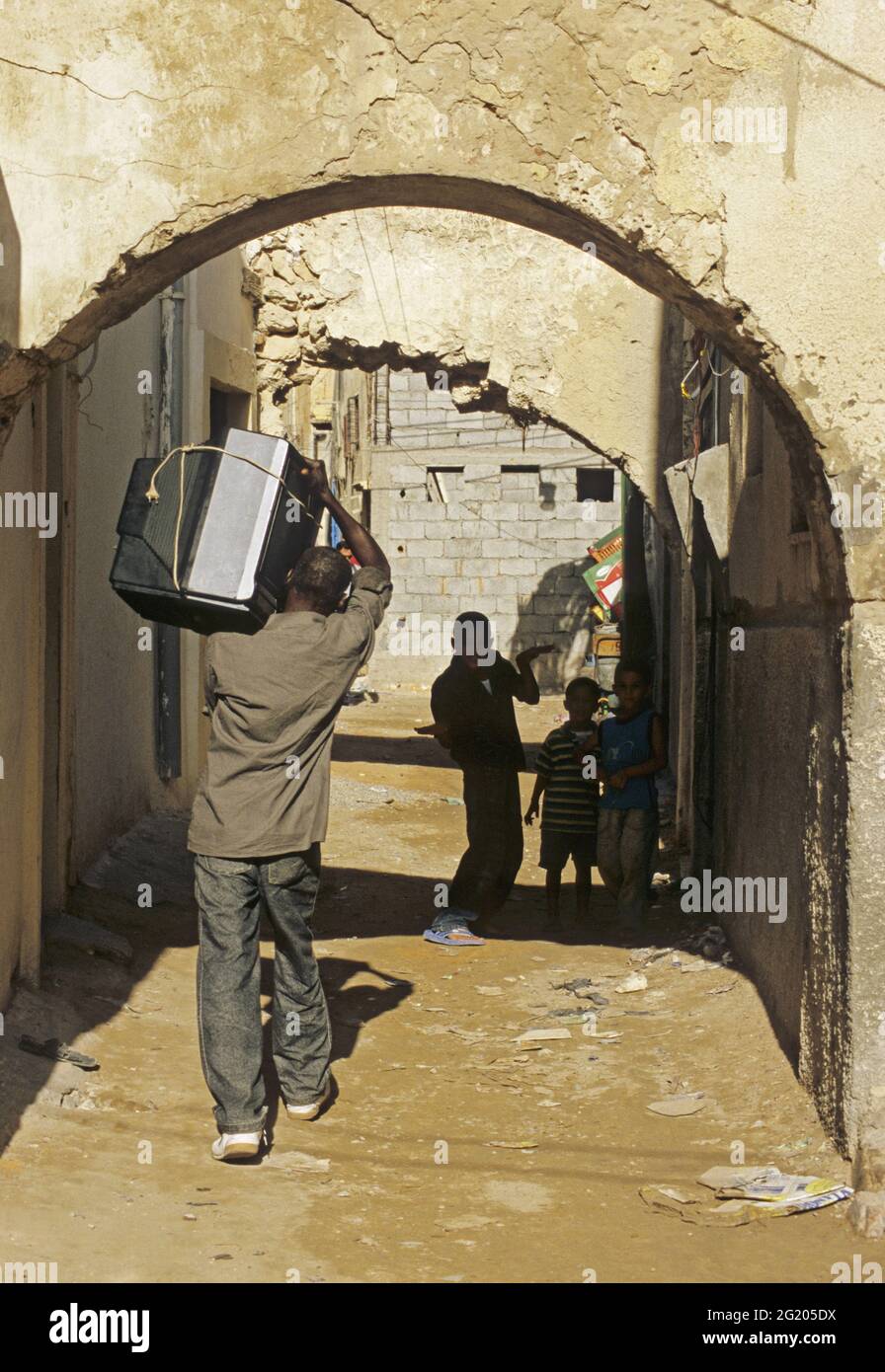 man carrying a television on his shoulder in the old medina of Tripoli, Libya Stock Photo