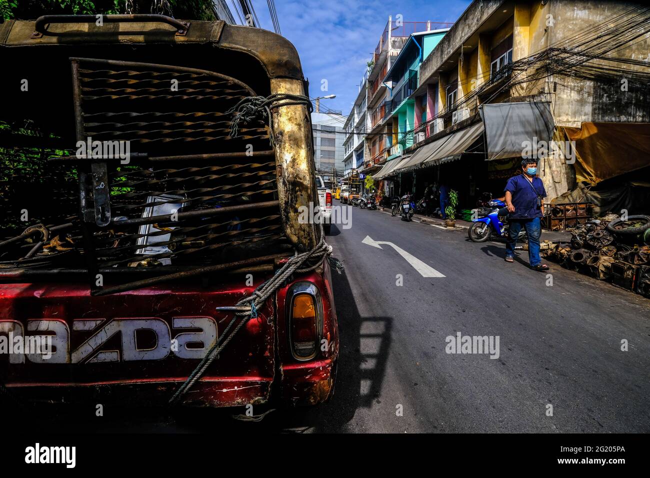 A narrow road containing a variety of automobile related workshops in Talat Noi, Bangkok, Thailand Stock Photo