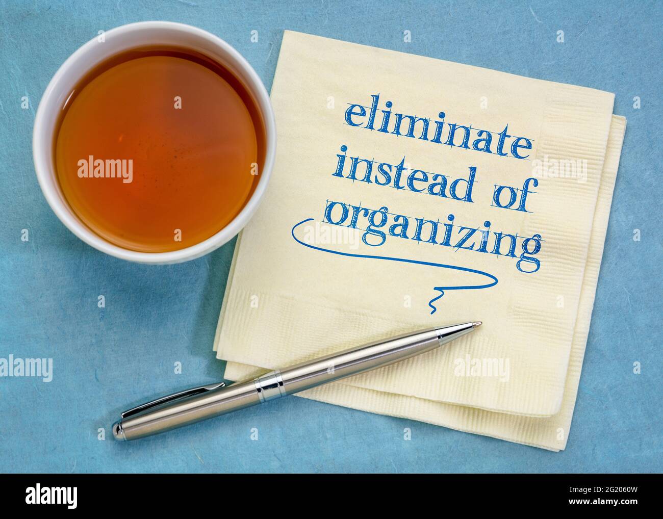 eliminate instead of organizing - handwriting on a napkin with a cup of tea, simplicity and decluttering concept Stock Photo