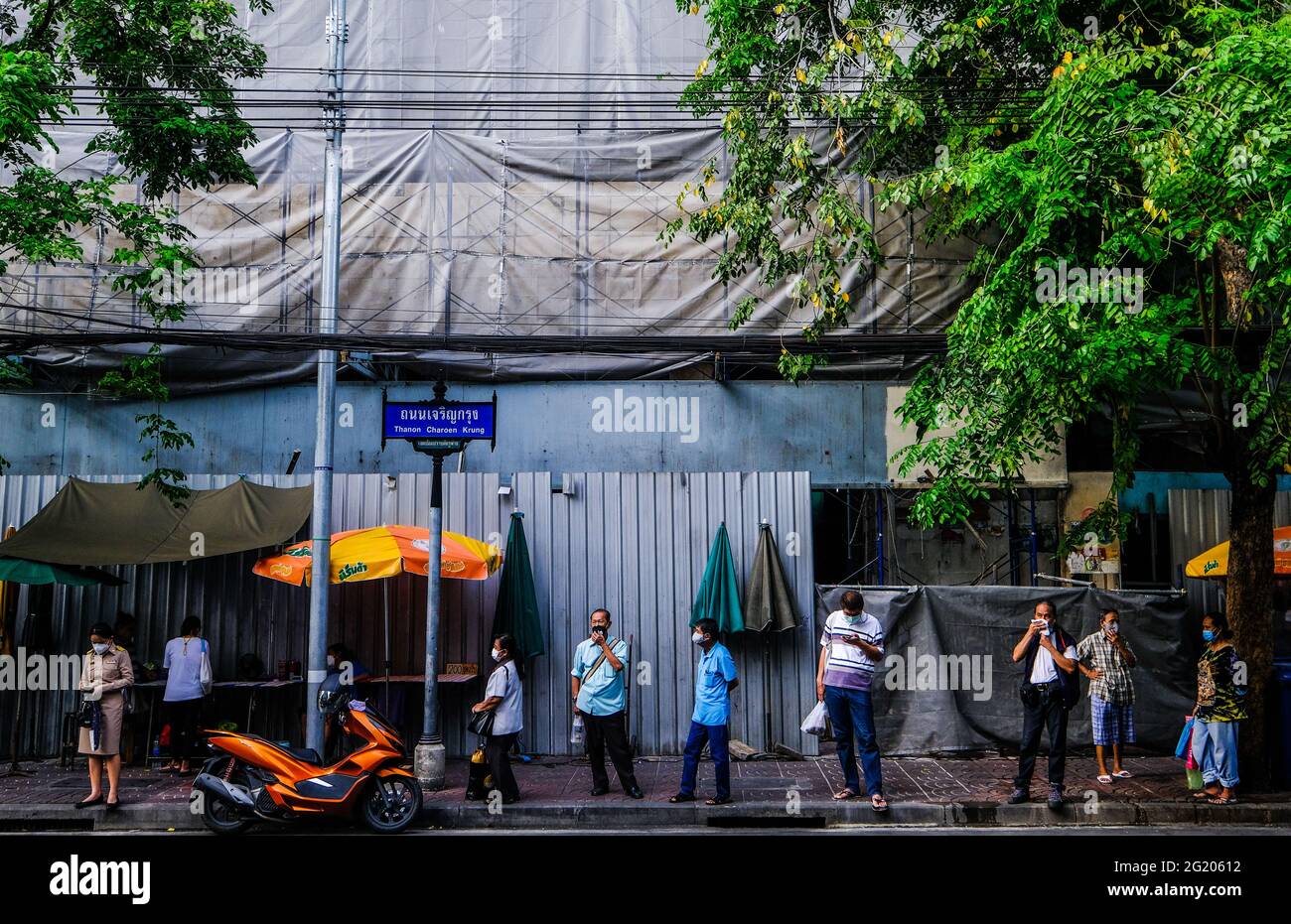 People wait for a bus on Charoen Krung Road, Bangkok, Thailand Stock Photo