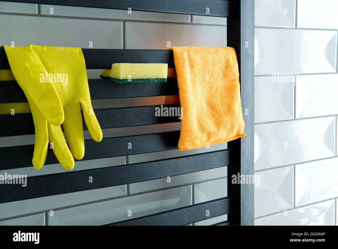 basic house cleaning equipment rubber glove, microfiber cloth and a spong hung on the bathroom