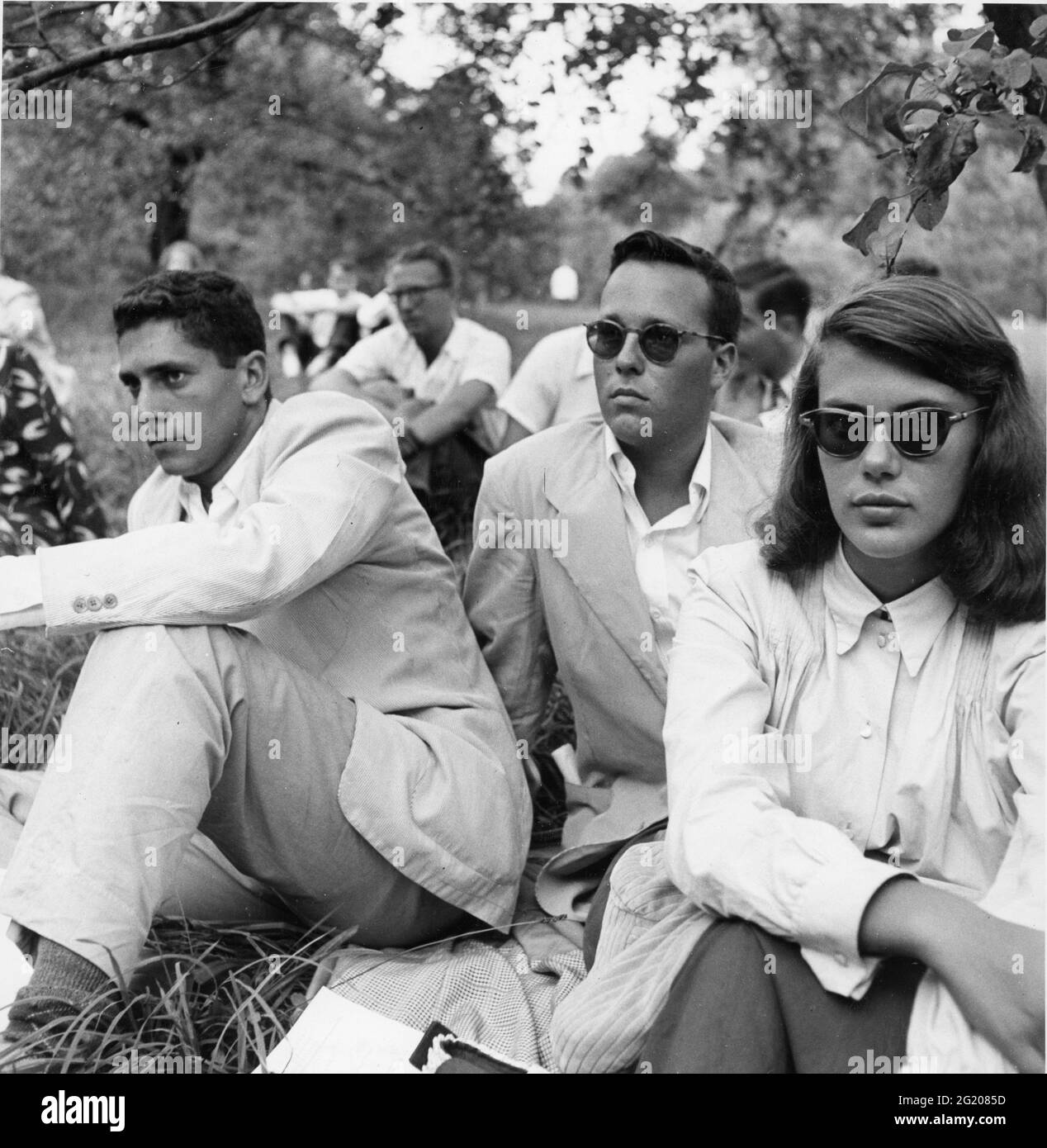 This attentive trio, seated on a grassy lawn, is listening to an outdoor choral concert at the Berkshire Music Festival at Tanglewood, Lenox, MA, August, 1949. (Photo by Speiser/US Department of State/RBM Vintage Images) Stock Photo