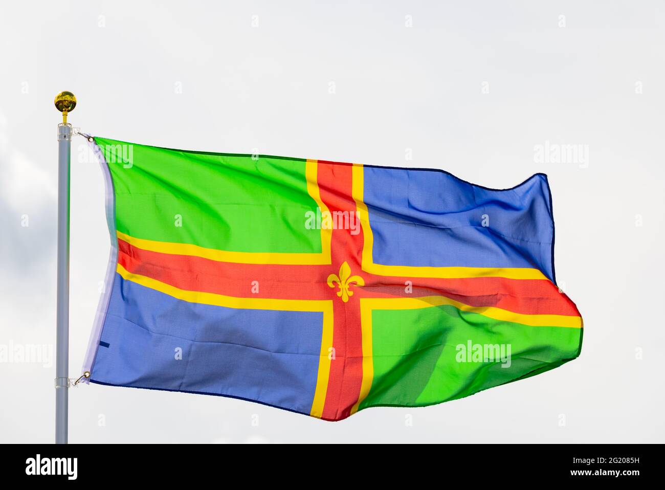 The flag of the county of Lincolnshire, flying against a white sky. Stock Photo