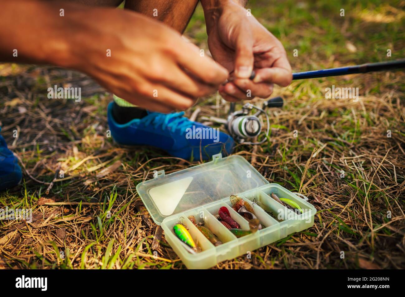 Young man attaching bait to hook of spinning. Fishing tackle. Man