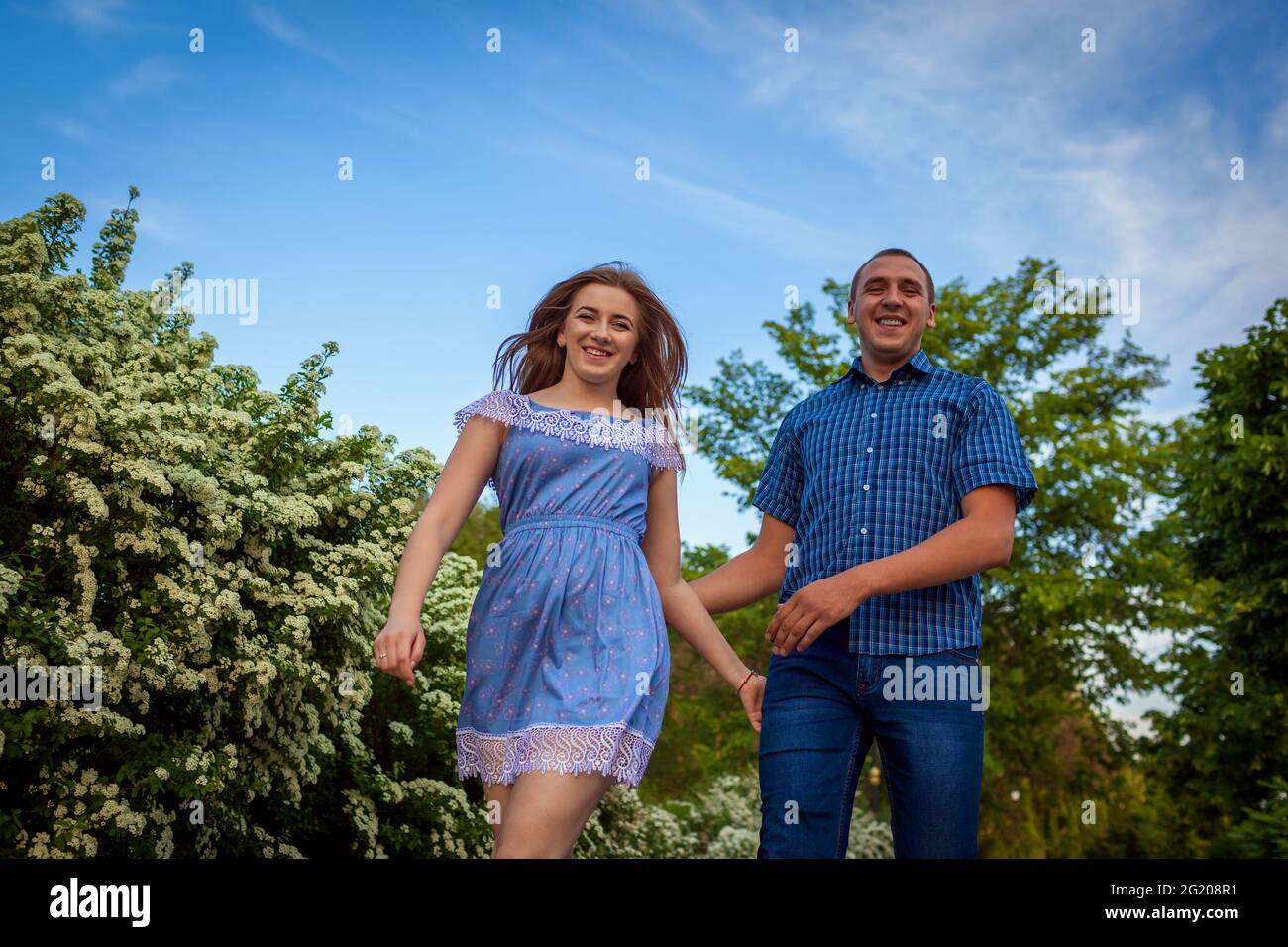 Couple running in spring blooming park. Young man and woman having fun at sunset. Stock Photo