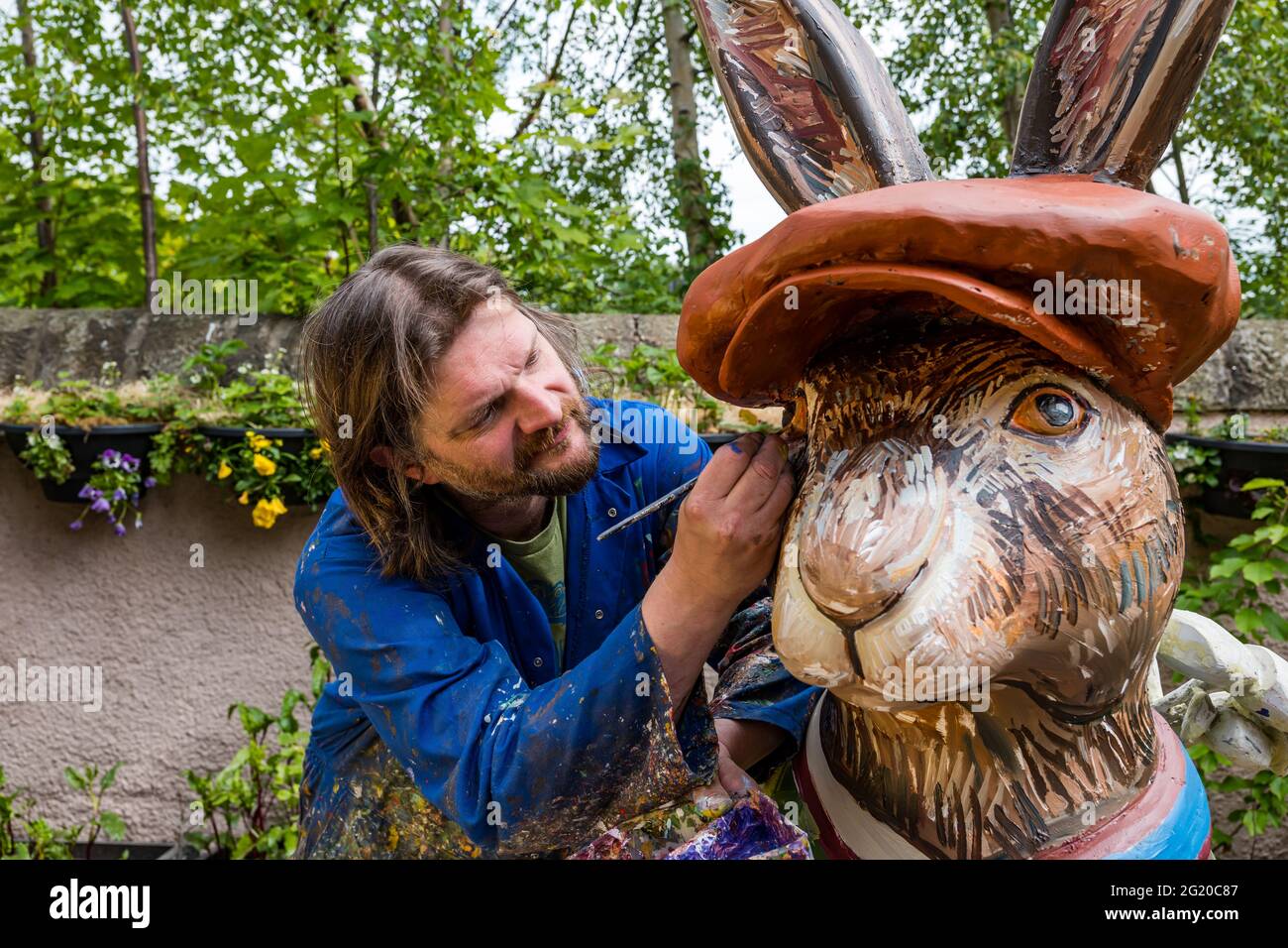 Artist Chris Rutterford paints a humorous giant fibreglass hare sculpture in his outdoor studio for a charity art trail, Scotland, UK Stock Photo