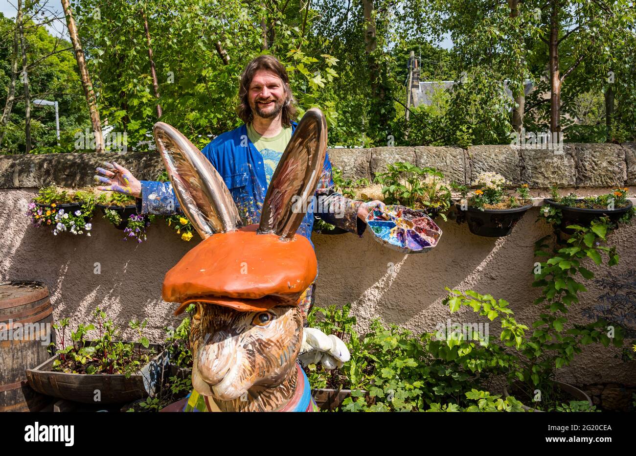 Artist Chris Rutterford paints a humorous giant fibreglass hare sculpture in his outdoor studio for a charity art trail, Scotland, UK Stock Photo