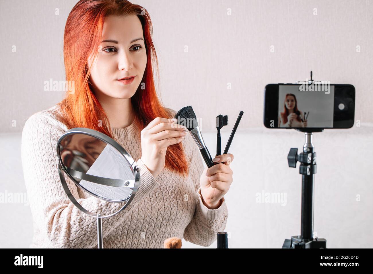 Woman beauty blogger records video content on her smartphone for your vlog. Modern influencer shows how to use cosmetics and make up. Online courses, Stock Photo