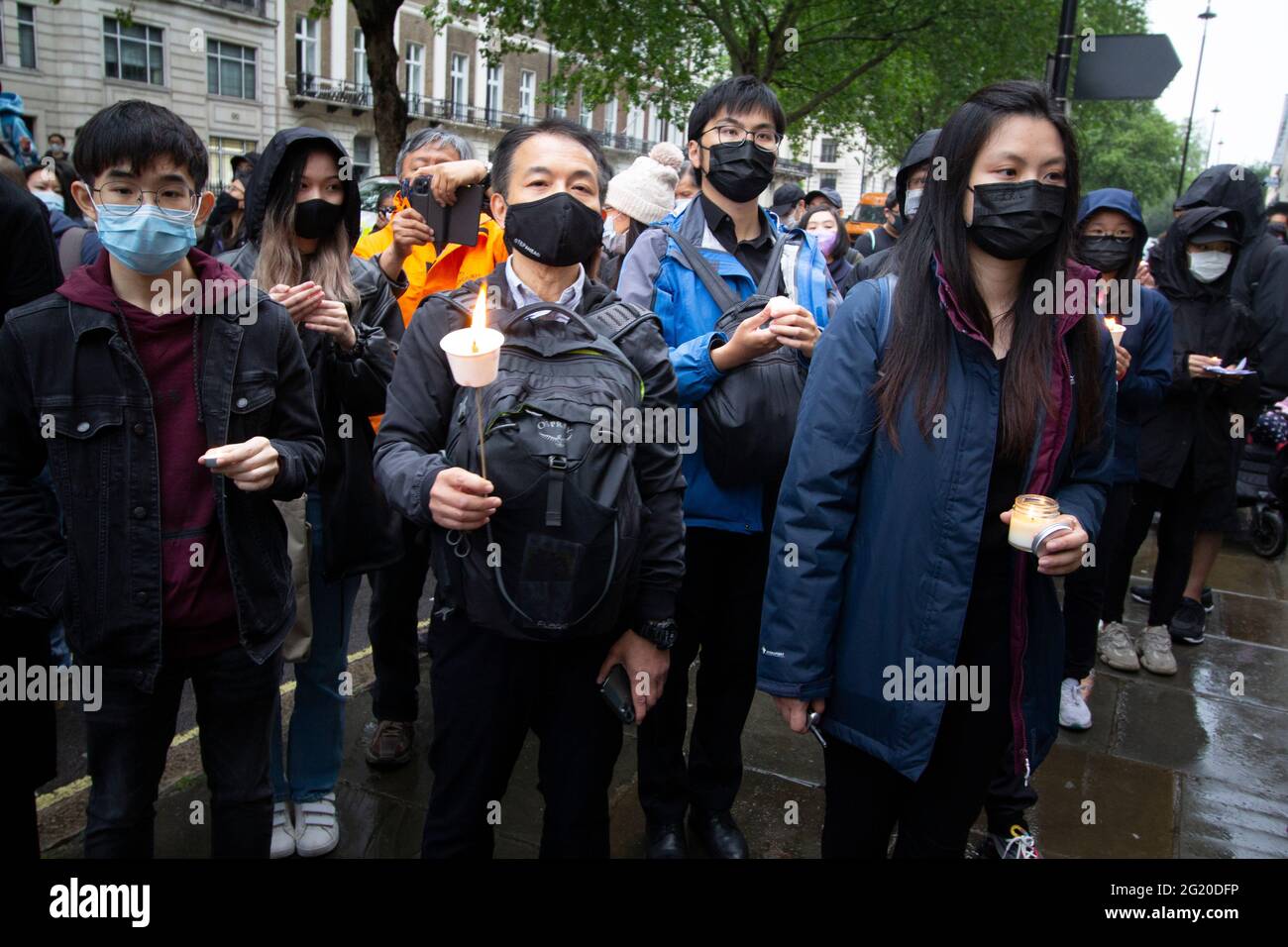 Masked Protesters Rally with candles opposite the  Chinese Embassy in London UK,  marking the 32nd anniversary of the  June 4th massacre at Tiananmen Square, China. Stock Photo