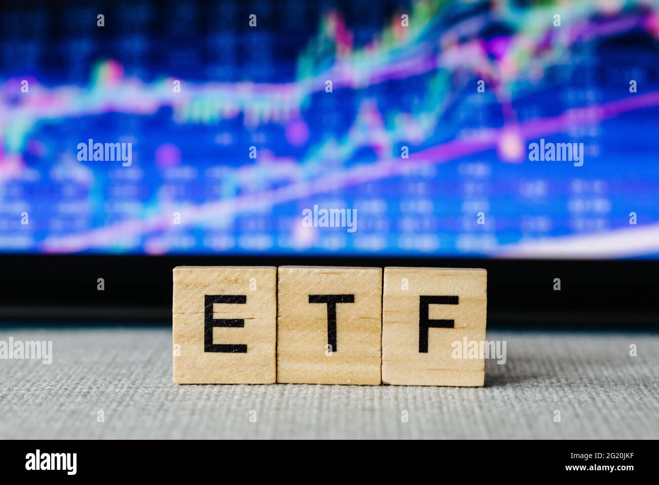 ETF Exchange-traded fund wooden letters and blurry stock market charts in the background Stock Photo