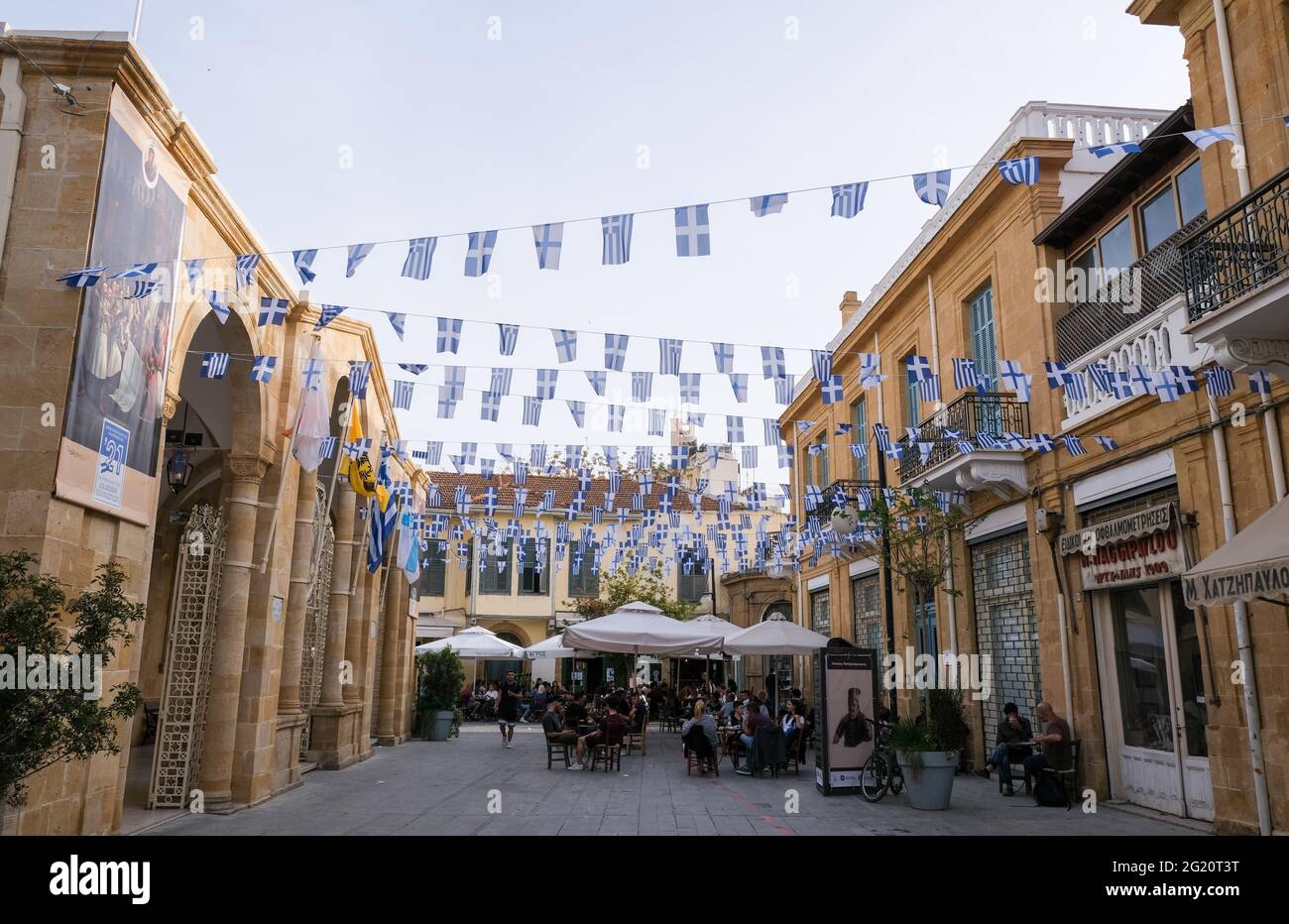 People relaxing at coffee shops and greek flags waving. Leadra street, Nicosia Cyprus Stock Photo
